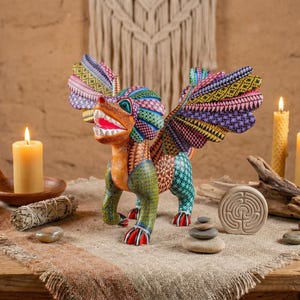 May include: A hand-carved wooden alebrije figurine featuring a mythical creature with wings, painted in vibrant patterns of green, orange, blue, and purple. The creature has an open mouth with white teeth and stands on four legs with red claws.