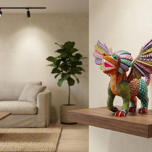 May include: A multi-coloured alebrije sculpture featuring a mythical creature with large, intricate wings, a wide open mouth showing teeth, and a vibrant, patterned body in shades of green, orange, yellow, purple, and blue, standing on a wooden shelf.