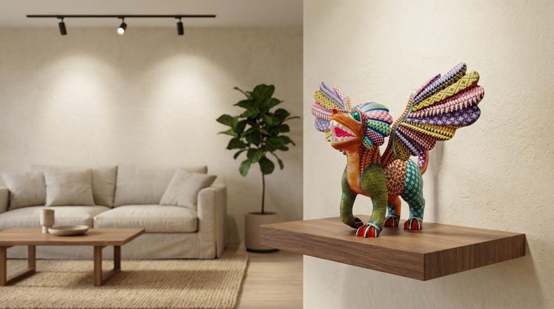 May include: A multi-coloured alebrije sculpture featuring a mythical creature with large, intricate wings, a wide open mouth showing teeth, and a vibrant, patterned body in shades of green, orange, yellow, purple, and blue, standing on a wooden shelf.