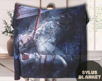 May include: A large, dark blue blanket featuring a detailed fantasy illustration. The artwork depicts a figure with long white hair and ornate armor, with red accents. The blanket has the text "SYLUS BLANKET" in a white circle.