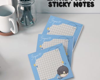 May include: Three blue sticky note pads with a grid pattern and the word "Zayne" written in white on each pad. The bottom pad features a cartoon illustration of a person with black hair and glasses.