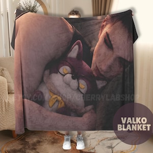 May include: A rectangular blanket featuring a printed illustration of a person embracing a plush animal character with dark fur, yellow eyes, and a yellow bow tie. The blanket displays the text VALKO BLANKET in the lower right corner.