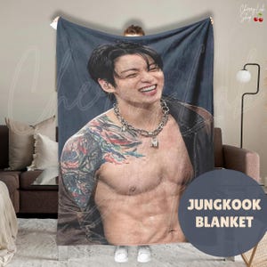 May include: A rectangular throw blanket featuring a large, high-resolution photographic print of a smiling person with dark hair, wearing a silver chain necklace and a dark jacket, with a colorful tattoo on their right shoulder and upper arm.