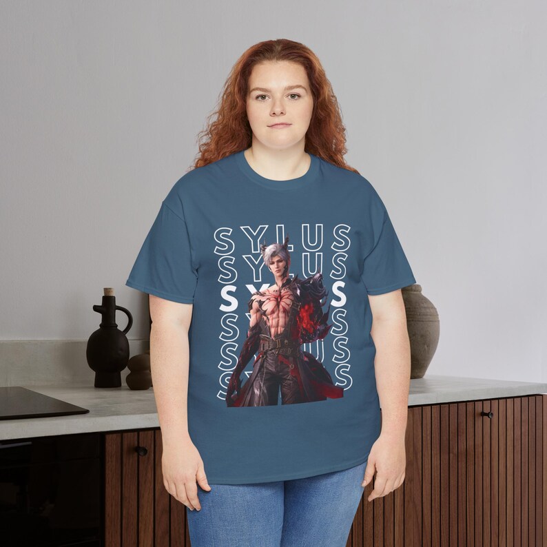 K&ouml;nnte beinhalten: Ein blaues T-Shirt mit kurzen &Auml;rmeln und einem Grafikdruck eines Charakters mit wei&szlig;em Haar und einem rot leuchtenden Arm. Der Name SYLUS wird in wei&szlig;en vertikalen Textspalten hinter dem Charakter wiederholt, was ein geschichtetes Design erzeugt.