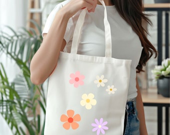 Peut inclure: Un sac fourre-tout en toile blanche avec des motifs de fleurs colorées. Les fleurs sont dans des tons de rose, orange, jaune et violet.