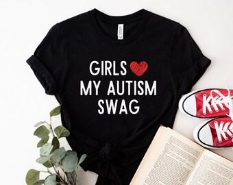 May include: Black t-shirt with white text that reads "Girls My Autism Swag" and a red heart.