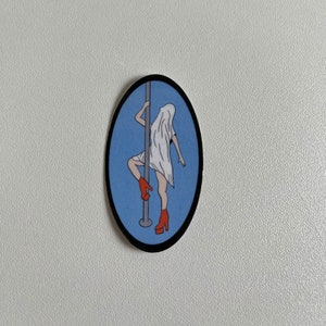 May include: Oval sticker featuring a cartoon illustration of a figure in a white sheet, red platform heels, and a pole. The figure is posed on a silver pole against a light blue background, with a black border.