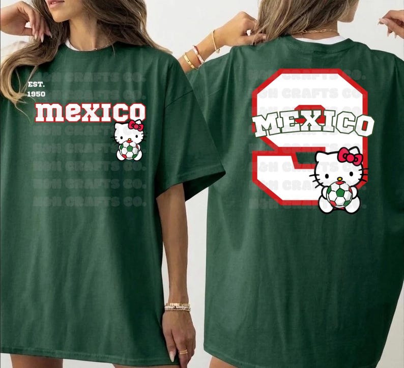 K&ouml;nnte beinhalten: Dunkelgr&uuml;nes T-Shirt mit dem Wort "MEXICO" in Rot und Wei&szlig; und einer Hello Kitty-Grafik, die einen Fu&szlig;ball h&auml;lt. Auf der R&uuml;ckseite befindet sich eine gro&szlig;e 9 mit "MEXICO" und eine weitere Hello Kitty-Grafik.