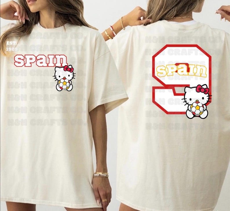 K&ouml;nnte beinhalten: Cremefarbenes T-Shirt mit dem Wort "SPAIN" in roter Schrift und einem Hello Kitty-Charakter, der einen Fu&szlig;ball h&auml;lt. Auf der R&uuml;ckseite des Shirts befindet sich eine gro&szlig;e 9 mit "SPAIN" darin und eine weitere Hello Kitty.