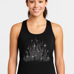 May include: Black racerback tank top with a rhinestone flame design. The flame design is made of small, sparkling rhinestones, creating a shimmering effect. The tank top is a classic, sleeveless style.