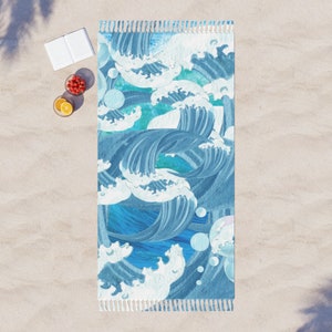 May include: A rectangular beach towel with a blue and white wave pattern. The design features stylized ocean waves in shades of blue, with white foam details. The towel has a fringed edge.