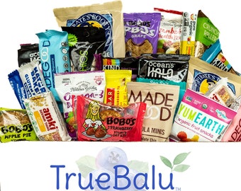 May include: A variety pack of individually wrapped snack bars and pouches. The snacks are colorful and feature a variety of flavors and brands, including Bobo's, Pirate's Booty, Made Good, and YumEarth. The snacks are arranged in a box with the logo "TrueBalu" and the tagline "Naturally Delicious Snacks".