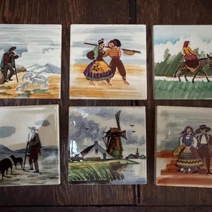 May include: A set of six square ceramic tiles featuring hand-painted scenes. The tiles depict various figures in traditional clothing, a person riding a donkey, a shepherd with animals, and a landscape scene with a windmill and a house.