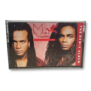 May include: A Milli Vanilli cassette tape. The cover features two men with long hair, one wearing an earring. The album title, "The Remix Album," is printed vertically on the right side. The band's logo is in the upper left.