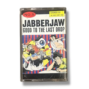 May include: A vintage cassette tape labeled "No. 5" with the title "Jabberjaw Good to the Last Drop." The cover features a colorful cartoon illustration with various characters, including an eyeball, a woman, and a man.