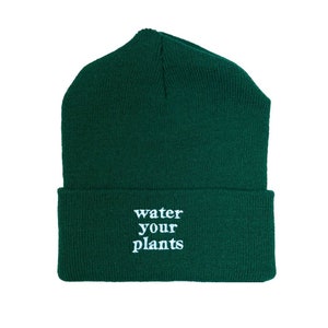 May include: A dark green beanie with the text "water your plants" embroidered in white.