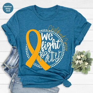 May include: A heather deep teal t-shirt with a yellow ribbon and the text "Childhood Cancer We Fight Together" in a white circle.