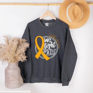 May include: A dark gray sweatshirt with a gold ribbon and the text "Childhood Cancer We Fight Together" in white.