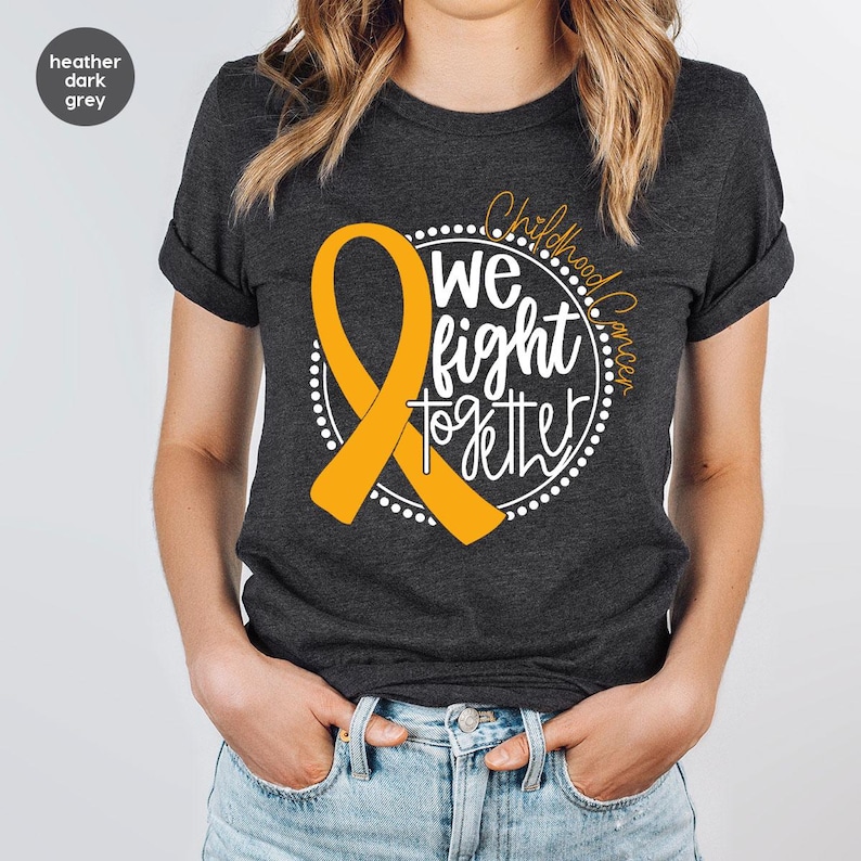 May include: Heather dark grey t-shirt with a gold ribbon and the text "Childhood Cancer We Fight Together" in a circle.