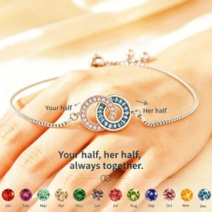 Puede incluir: Una pulsera plateada con dos círculos entrelazados, uno con piedras rosas y otro con piedras azules. El texto dice: "Your half, her half, always together." Debajo se muestran piedras de nacimiento para cada mes.