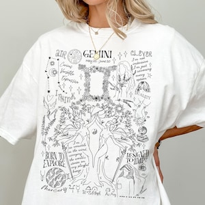 Op de afbeelding: Wit overhemd met een zwarte grafische print van een boom met astrologische symbolen en de tekst "AIR GEMINI CLEVER May 21-June 20 Caring Versatile Expressive I THINK BORN TO EXPLORE I'm the variable energy saving the world's stories on every planet Mercury 240 120-264 DESIGNED TO ADAPT".