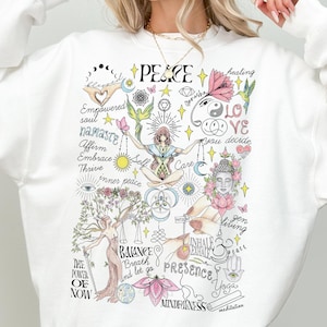 May include: White sweatshirt with a graphic print of a tree with various words and symbols related to peace, love, and mindfulness. The words include "peace", "love", "balance", "presence", "mindfulness", "namaste", "empowered", "thrive", "inner peace", "breath", "and let go", "inhale exhale", "yoga", "meditation", "you decide", "gen living", "the power of now", and "care".