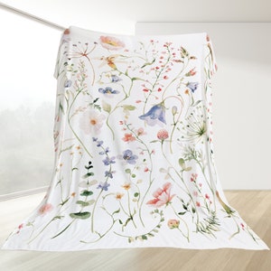 May include: White throw blanket with a watercolour floral print featuring pink, blue, and green flowers and leaves.