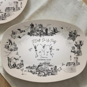 Puede incluir: Una taza de cerámica blanca con un asa negra y el texto "But First, Coffee" en negrita negra. La taza se encuentra sobre un fondo neutro, resaltando su diseño sencillo.