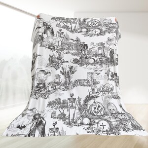 May include: Black and white Halloween themed throw blanket with a spooky, gothic design featuring skeletons, pumpkins, and other Halloween imagery.