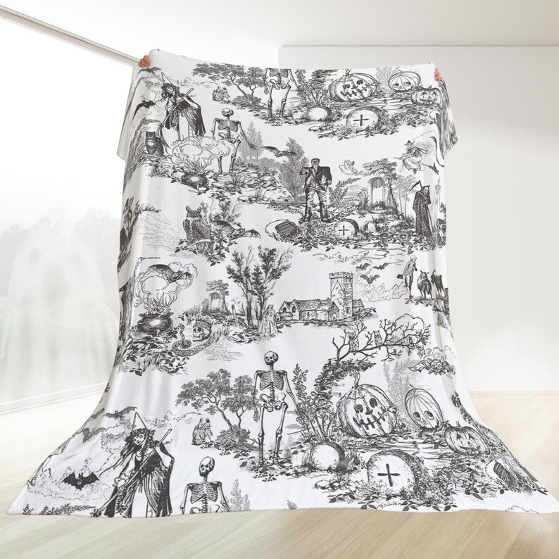 May include: Black and white Halloween themed throw blanket with a spooky, gothic design featuring skeletons, pumpkins, and other Halloween imagery.