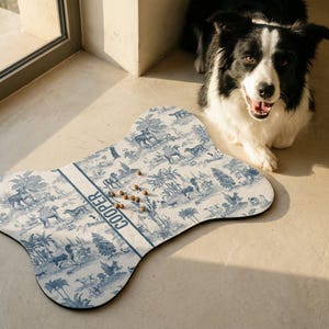 A black and white dog is sitting on a beige floor next to a bone-shaped dog toy with a pattern of animals and trees.