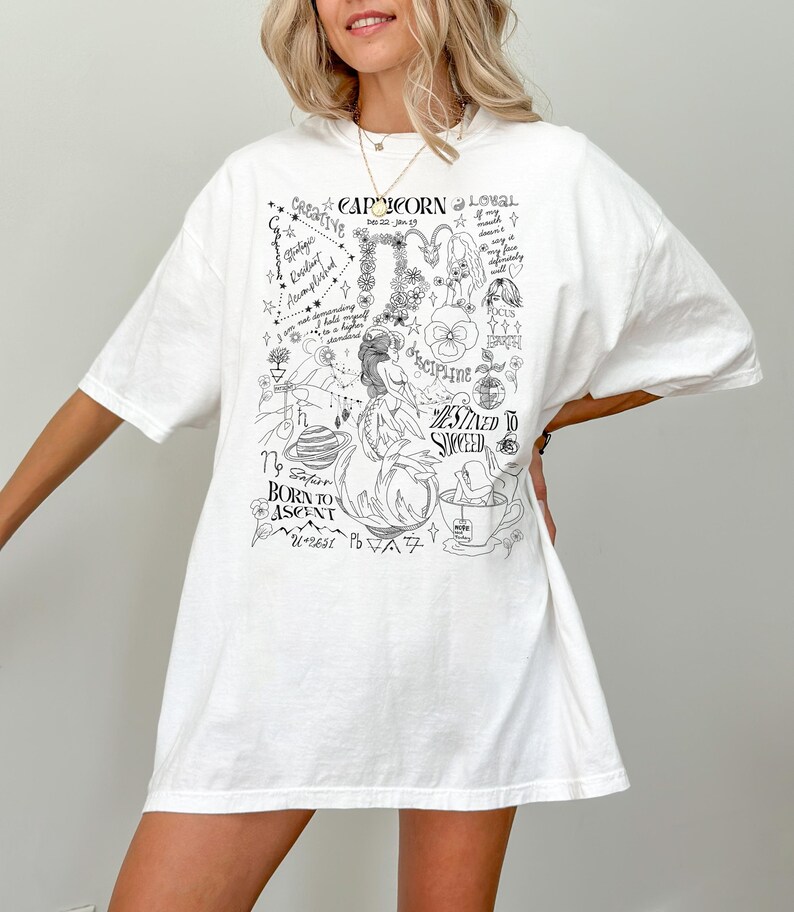 May include: White oversized t-shirt with a black and white graphic print of a Capricorn zodiac sign with various symbols and text, including "Capricorn", "Creative", "Loyal", "Disciplined", "Destined to Succeed", "Born to Ascend", and "Dec 22 - Jan 19".