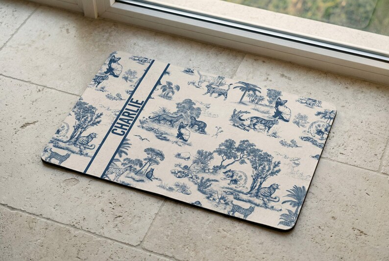 A decorative mat with a blue and white pattern featuring various animals and scenes, placed on a tiled floor near a window.