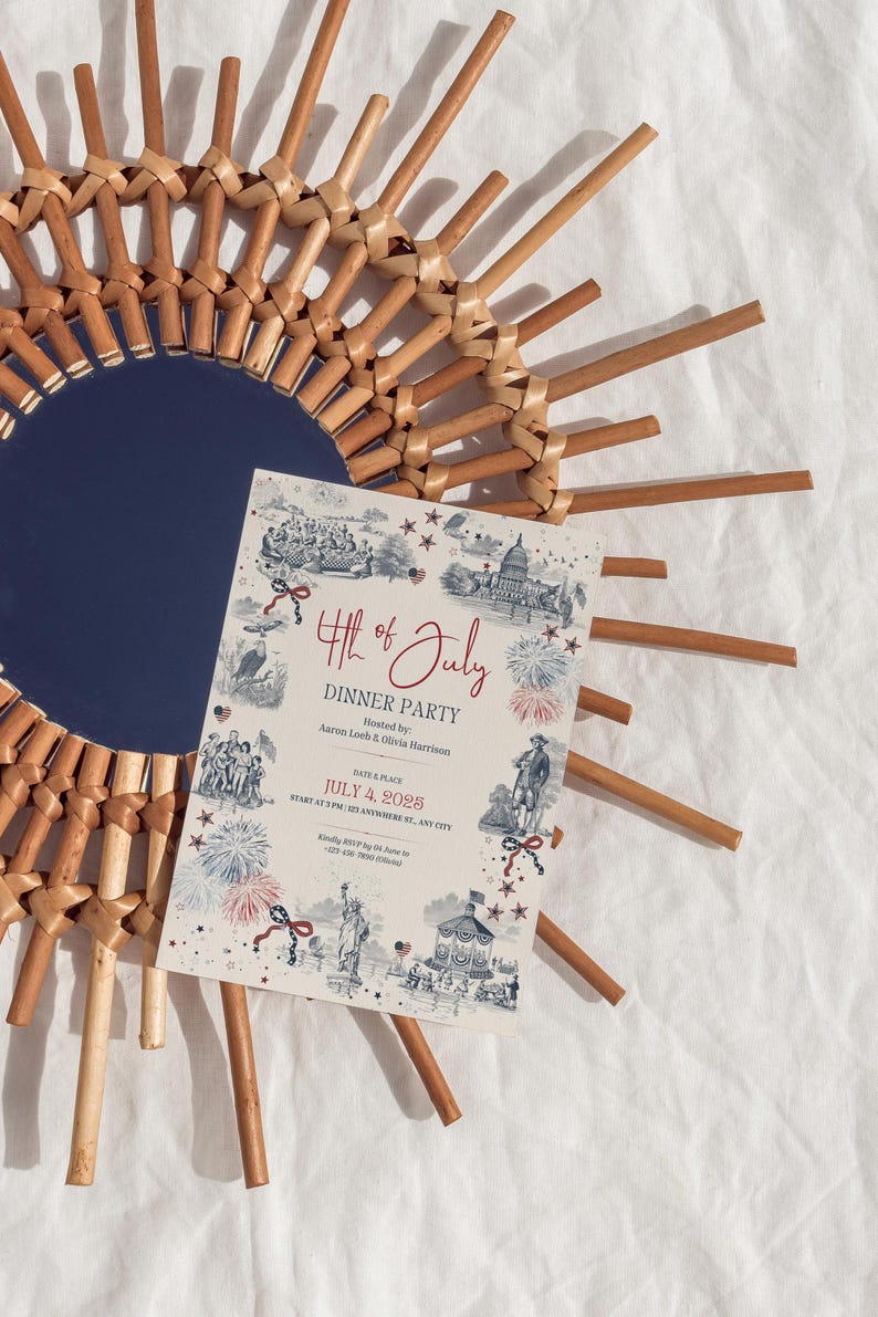 May include: A decorative 4th of July dinner party invitation with a vintage design, featuring illustrations of historical figures and landmarks. The invitation is placed on a woven sunburst mirror with a navy blue center.