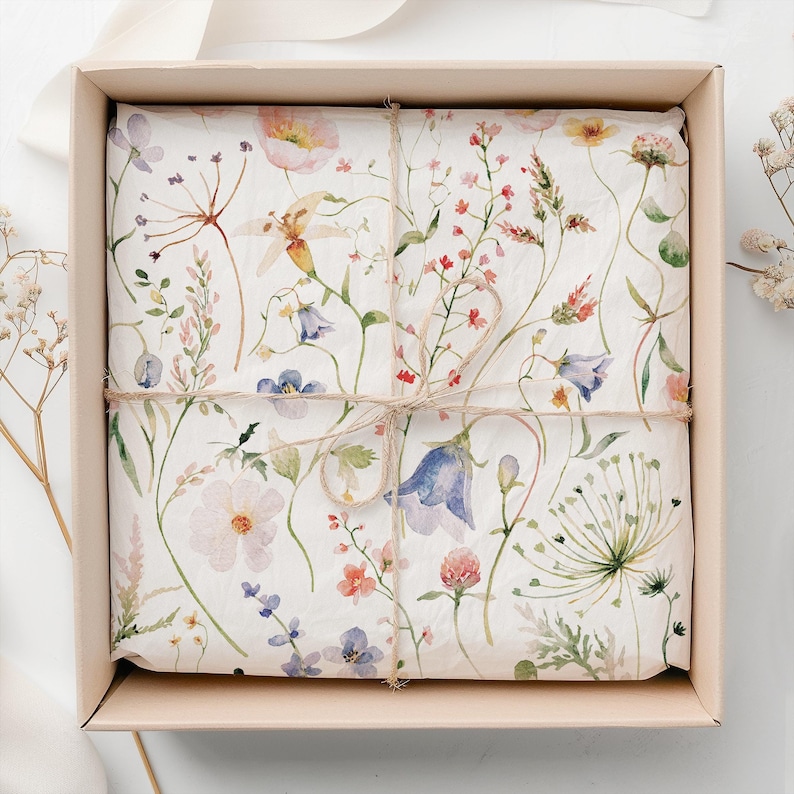 May include: A white gift box with a floral patterned wrapping paper. The paper features a delicate watercolor design of pink, blue, and green flowers and leaves.