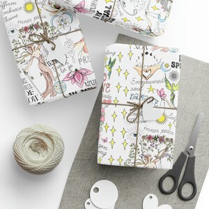 May include: Three white gift boxes wrapped in paper with colorful illustrations and text. The paper features a variety of designs, including flowers, stars, birds, and hands. The text includes phrases like "inner peace", "empowered soul", and "namaze".