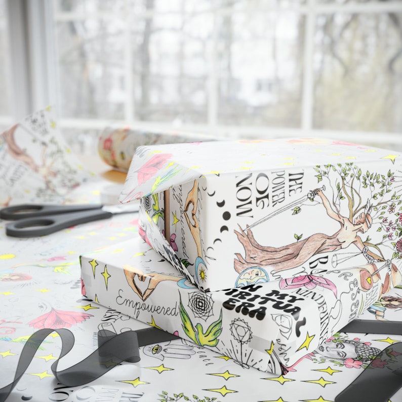 May include: Two gift boxes wrapped in white paper with colorful illustrations. The top box features a woman holding a sword and a tree with the text "The Power Of Now". The bottom box features a variety of illustrations including a hand with the text "Empowered".