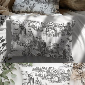 May include: Three white throw pillows with a black and white Halloween-themed toile pattern. The pillows feature images of skeletons, pumpkins, bats, and other spooky elements. The middle pillow has the name "Olivia" printed on it.
