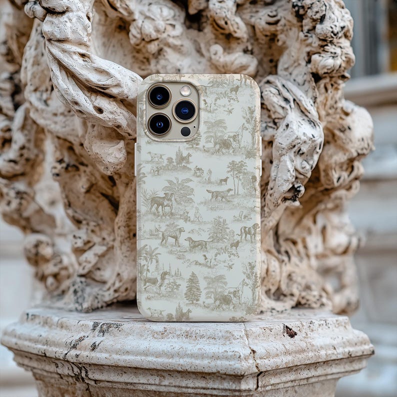 Op de afbeelding: Een witte iPhone-hoes met een beige en bruin patroon van bomen en dieren. De hoes heeft een uitsparing voor de camera en een gouden rand.