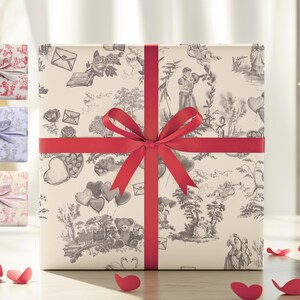 Pu&ograve; includere: Una scatola regalo bianca con un motivo bianco e nero di cuori, fiori e uccelli. La scatola &egrave; legata con un nastro rosso e un fiocco.