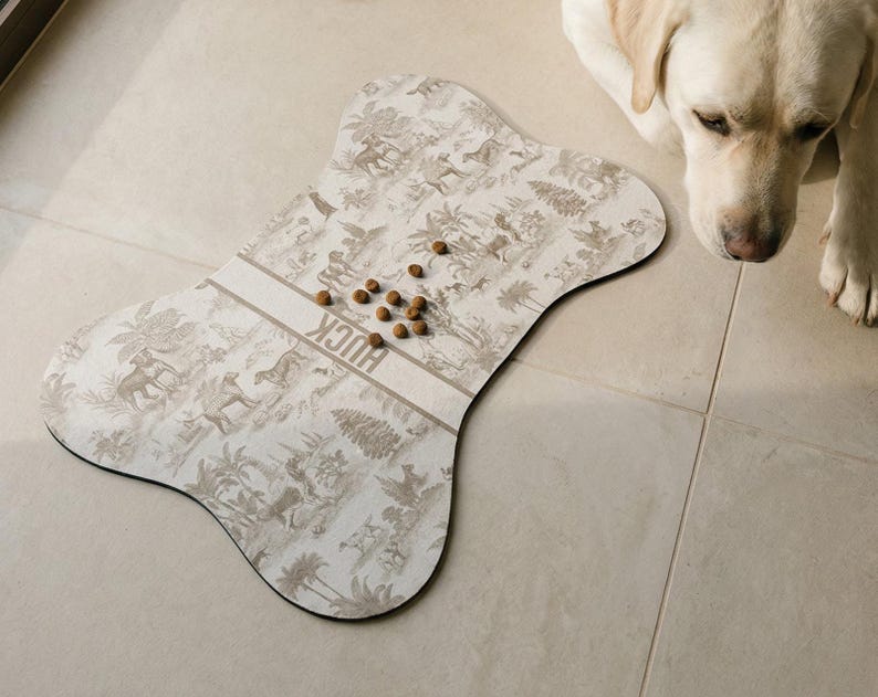 A dog is sitting on a tiled floor next to a large bone-shaped dog toy, which has several dog treats scattered on it.