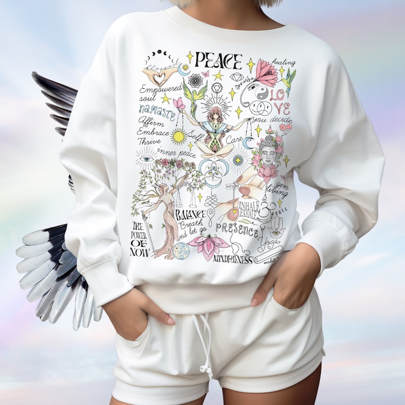 May include: White sweatshirt with a colorful graphic print featuring the word "PEACE" and various symbols and phrases related to mindfulness, yoga, and self-care. The graphic includes phrases like "inner peace", "balance", "presence", and "mindfulness".