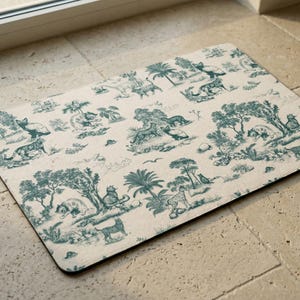 a decorative mat with a repeating pattern of various animals and natural elements, such as palm trees, birds, and other wildlife, all set against a light background.