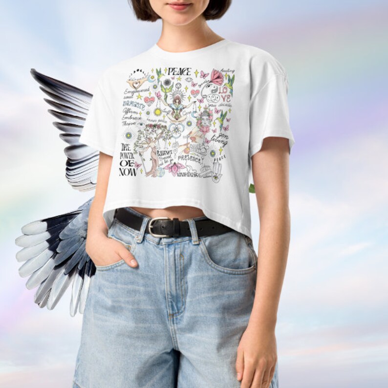 May include: White cropped t-shirt with a colorful graphic print featuring various symbols, words, and illustrations. The design includes words like "Peace", "Love", "The Power of Now", and "Presence".
