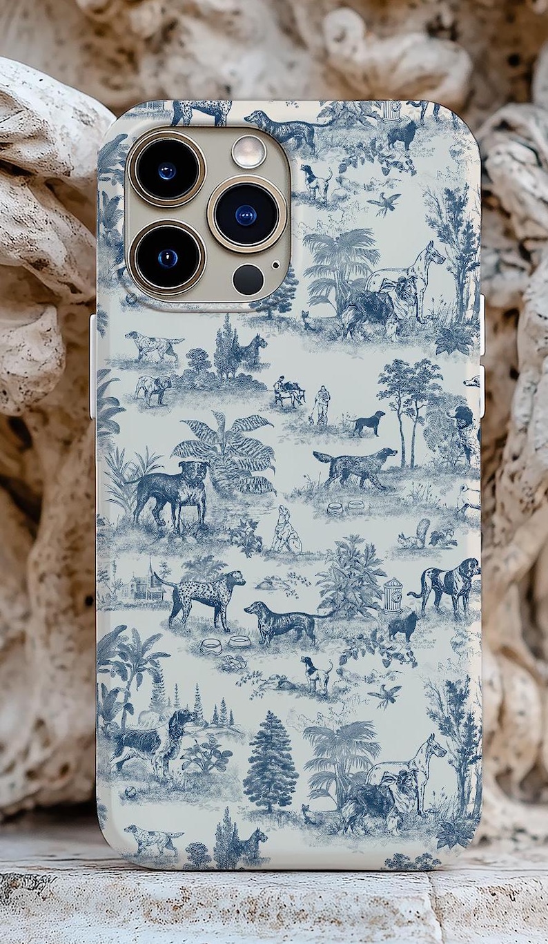 Op de afbeelding: Een witte iPhone-hoes met een blauw-wit toile-patroon met honden, bomen en andere natuur-ge&iuml;nspireerde ontwerpen.