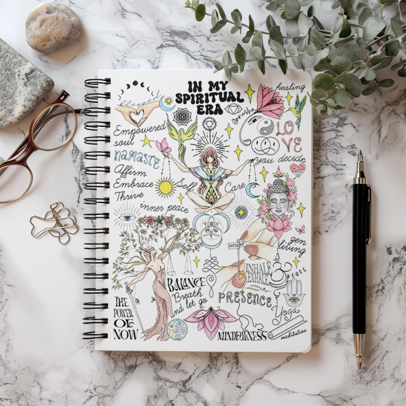 Peut inclure: Un carnet &agrave; spirales blanc pr&eacute;sentant une illustration d&eacute;taill&eacute;e avec le texte In My Spiritual Era. Le motif comprend une figure centrale en position du lotus, entour&eacute;e de divers symboles comme une fleur de lotus, une t&ecirc;te de Bouddha et du texte.
