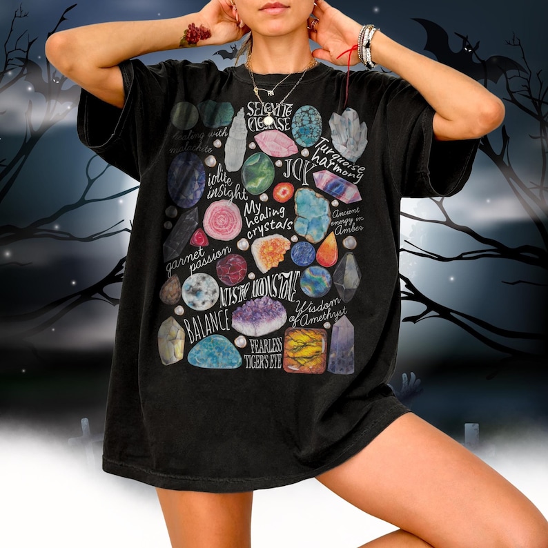 Puede incluir: Camiseta negra con un estampado gr&aacute;fico de varios cristales y sus significados asociados, incluyendo limpieza de selenita, intuici&oacute;n de iolite, armon&iacute;a turquesa, pasi&oacute;n de granate, sabidur&iacute;a de amatista y ojo de tigre sin miedo.