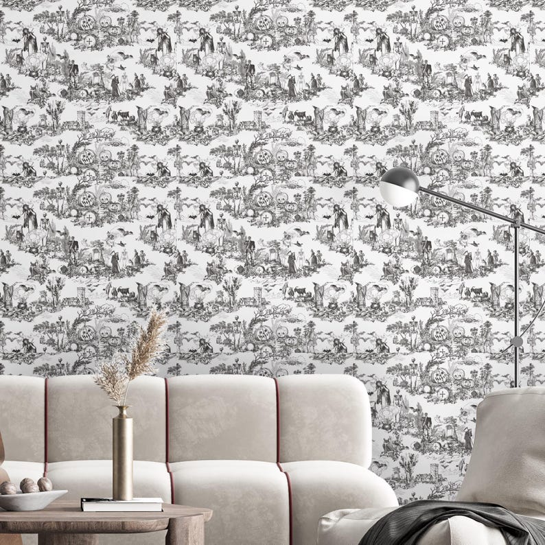 May include: Black and white Halloween-themed wallpaper featuring a repeating toile pattern. The design includes pumpkins, bats, skeletons, and other spooky elements. The wallpaper is displayed on a wall behind a beige sofa and a wooden table.