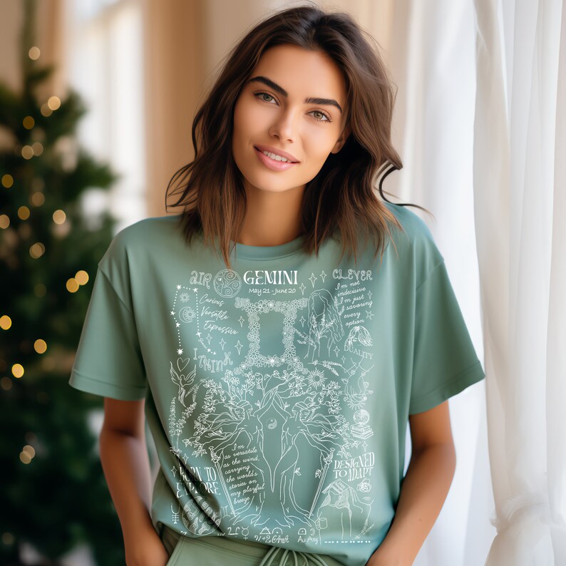 Op de afbeelding: Een saliegroen T-shirt met een wit grafisch ontwerp met het sterrenbeeld Tweelingen en astrologische symbolen. De tekst "AIR GEMINI CLEVER MAY 21 - JUNE 20" is op het shirt gedrukt.