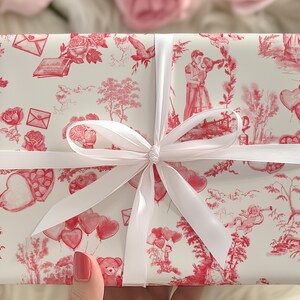 Pu&ograve; includere: Carta da regalo bianca con un motivo rosso e bianco di cuori, fiori e altri disegni romantici. Il regalo &egrave; legato con un nastro di raso bianco.